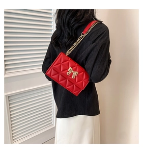 Detailed macro view of red quilted leather bag with a golden bow metal buckle detail