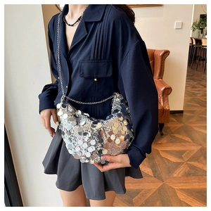 Detail of silver sequin hobo bag with a metallic chain strap in a fashion lifestyle setting