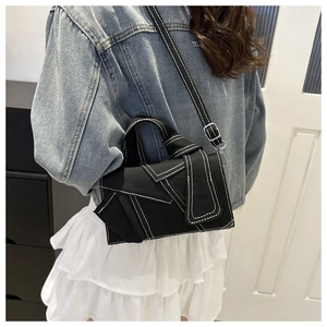 Détail du sac bandoulière en denim noir déconstruit avec doubles surpiqûres blanches