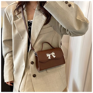 Dettaglio mini borsa a tracolla in pelle marrone scuro con chiusura a fiocco argento
