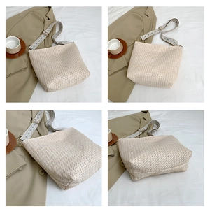 Detail view of a beige woven straw tote bag featuring a geometric pattern shoulder strap