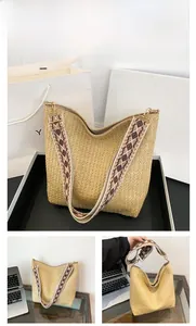Detail of khaki woven straw hobo bag with ethnic pattern wide adjustable strap