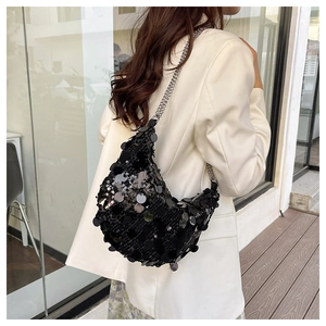 Detail of a sparkling black sequin crescent shoulder bag with a thin silver chain strap