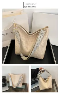 Detail of hobo straw woven bag in cream white with ethnic geometric pattern wide strap
