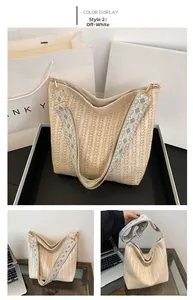 Detail of beige straw hobo bag with wide geometric patterned strap and gold hardware