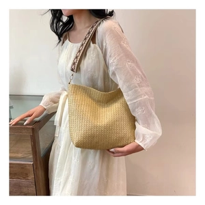 Gros plan détaillé du sac en paille avec large bandoulière à motif ethnique géométrique