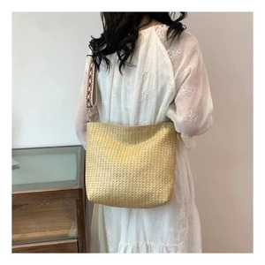 Detailed view of woven straw tote bag featuring a geometric pattern wide shoulder strap