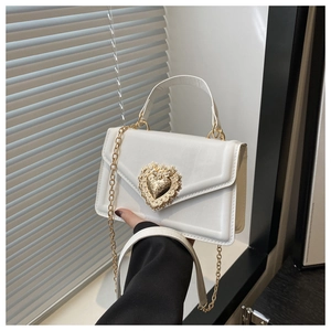 Détail du sac bandoulière blanc avec boucle cœur dorée et décorations en perles