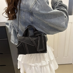 Chic black crossbody bag with white contrast stitching and geometric denim patchwork detail