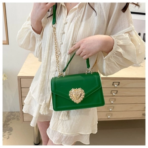 Détail du sac à main vert avec boucle cœur dorée et décorations en perles raffinées