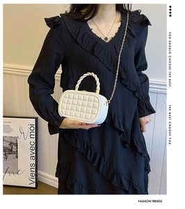 Detail of white quilted mini box bag with gold chain strap and woven handle texture