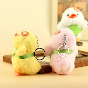 Dettaglio di portachiavi a forma di anatra in peluche giallo e rosa con fiori ricamati