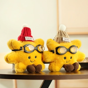 Detail of plush star keychains with goggles, knit hats, and embroidered faces on wood