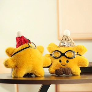 Close-up of yellow plush star pendants with knit hats and goggles on wooden surface
