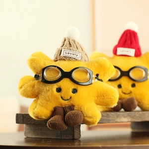 Close-up of a plush star toy with embroidered face, yellow fur, and a knit beanie