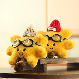 Detail of plush star keychains wearing knit hats and goggles on a wooden shelf