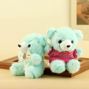 Dettaglio di orsetto di peluche verde menta con fiocco di pizzo e maglione lavorato