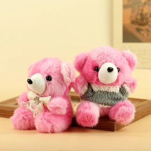 Dettaglio di orsetti di peluche rosa con fiocco in pizzo bianco e maglione grigio a maglia