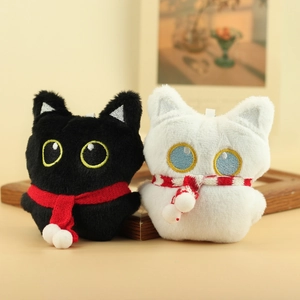 Detail van schattige zwarte en witte pluche kattenhangers met sjaaltjes op een huiselijke tafel