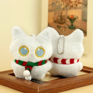 Detailopname van witte pluche katten-sleutelhangers met gestreepte sjaals en borduur