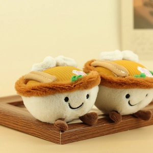 Macro shot of two cute plush bowl noodle charms on a warm wooden frame background