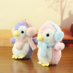 Plush penguin keychains in purple and pink with cozy earmuffs on a wooden surface