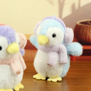 Close-up of cute plush penguin keychain with earmuffs and scarf on a wooden table