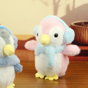 Close-up of a pink plush penguin doll with blue earmuffs and soft faux fur texture