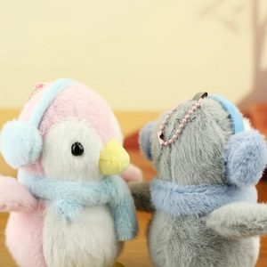 Close-up of plush penguin charms with ear muffs, scarves and pink beaded chains