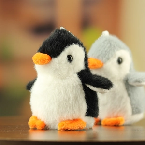 Close-up van schattige pluche pinguïn sleutelhangers in zwart en grijs met metalen kettingen