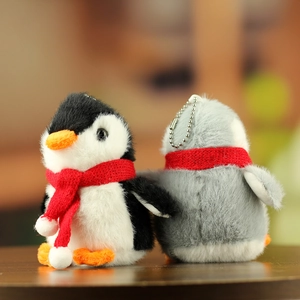 Close-up of cute plush penguin keychains in black and grey with red knitted scarves