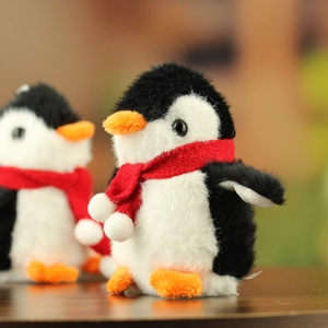 Close-up of cute plush penguin couple with soft fur and tiny red knitted scarves