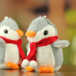 Close-up of cute penguin plush keychain with soft fur and a festive red scarf detail
