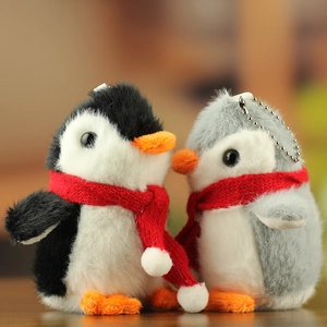 Close-up of cute plush penguin pendants with red knit scarves and silver metal chains