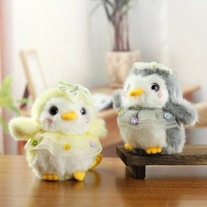 Detail of plush penguin keychains with lace collars and bows on a wooden tray