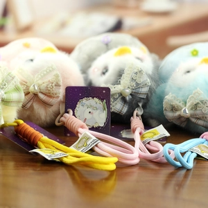Close-up of cute plush penguin keychains with lace bows and pastel braided ropes