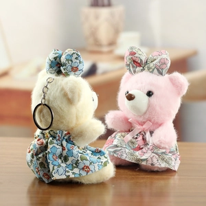 Détail de peluches ours en robes florales avec anneaux métalliques sur bois