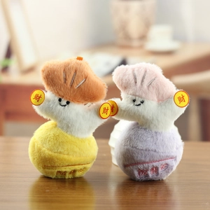 Simpatici ciondoli di peluche con volti sorridenti e monete della fortuna su tavolo in legno