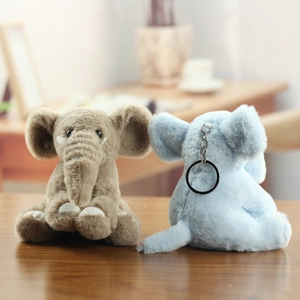 Cute plush elephant keychains in brown and blue colors on a wooden background