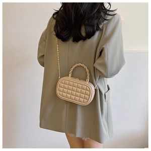 Detail view of beige quilted box bag with knot handle and gold chain strap on model
