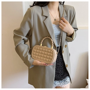 Detail of khaki woven box bag featuring chunky twist handle and gold chain strap