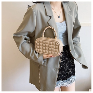 Detail of beige woven box bag with textured check pattern and gold chain strap