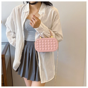 Close-up of pink quilted box bag with gold chain strap and textured woven pattern