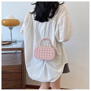 Detail of light pink box bag showing quilted texture and golden woven metal handle