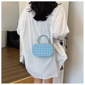 Detail of light blue quilted mini bag with chic gold chain and twisted rope handle