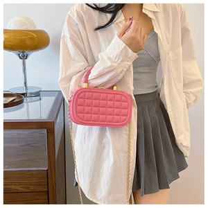 Pink quilted mini box bag with woven handle and gold chain strap shown on model