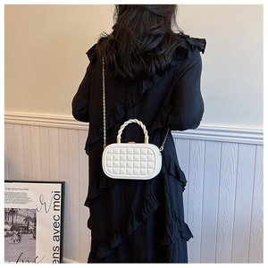 Close-up of white quilted chain bag with gold hardware and spiral handle on model