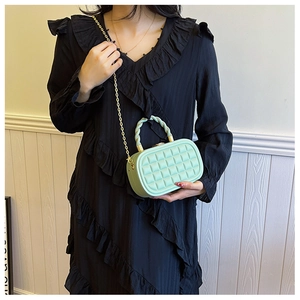 Detailed shot of mint green quilted box bag with woven handle and gold chain strap