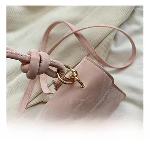 Détail d'un sac bandoulière rose en cuir verni à motif marbré et ferrures dorées