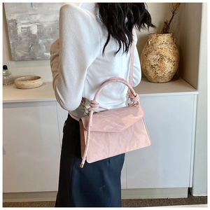 Pink pleated handbag for women with knot handle detail shown in a modern interior setting